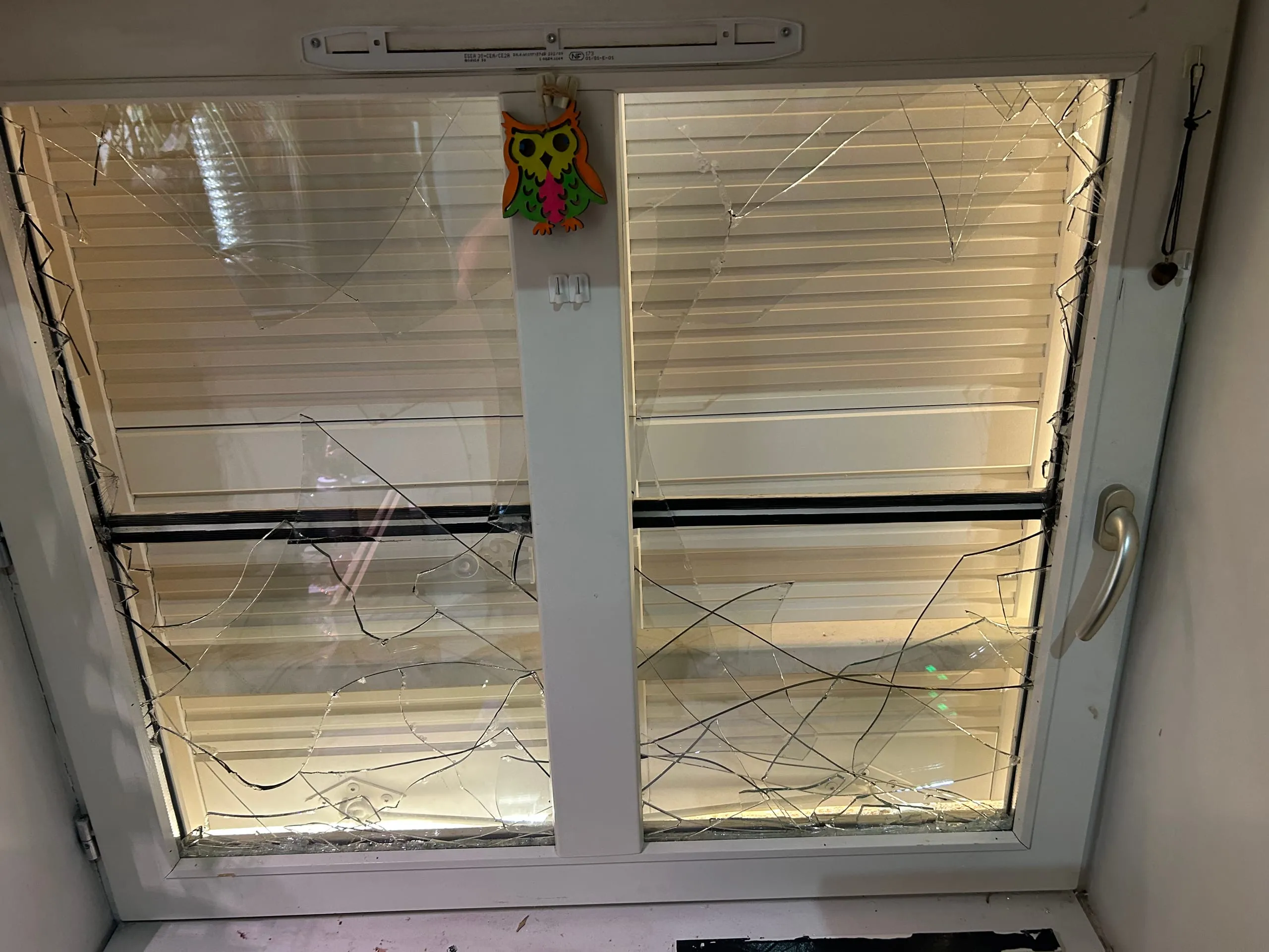 Deux vitrages fortement brisés dans une fenêtre PVC blanche après le passage des pompiers.