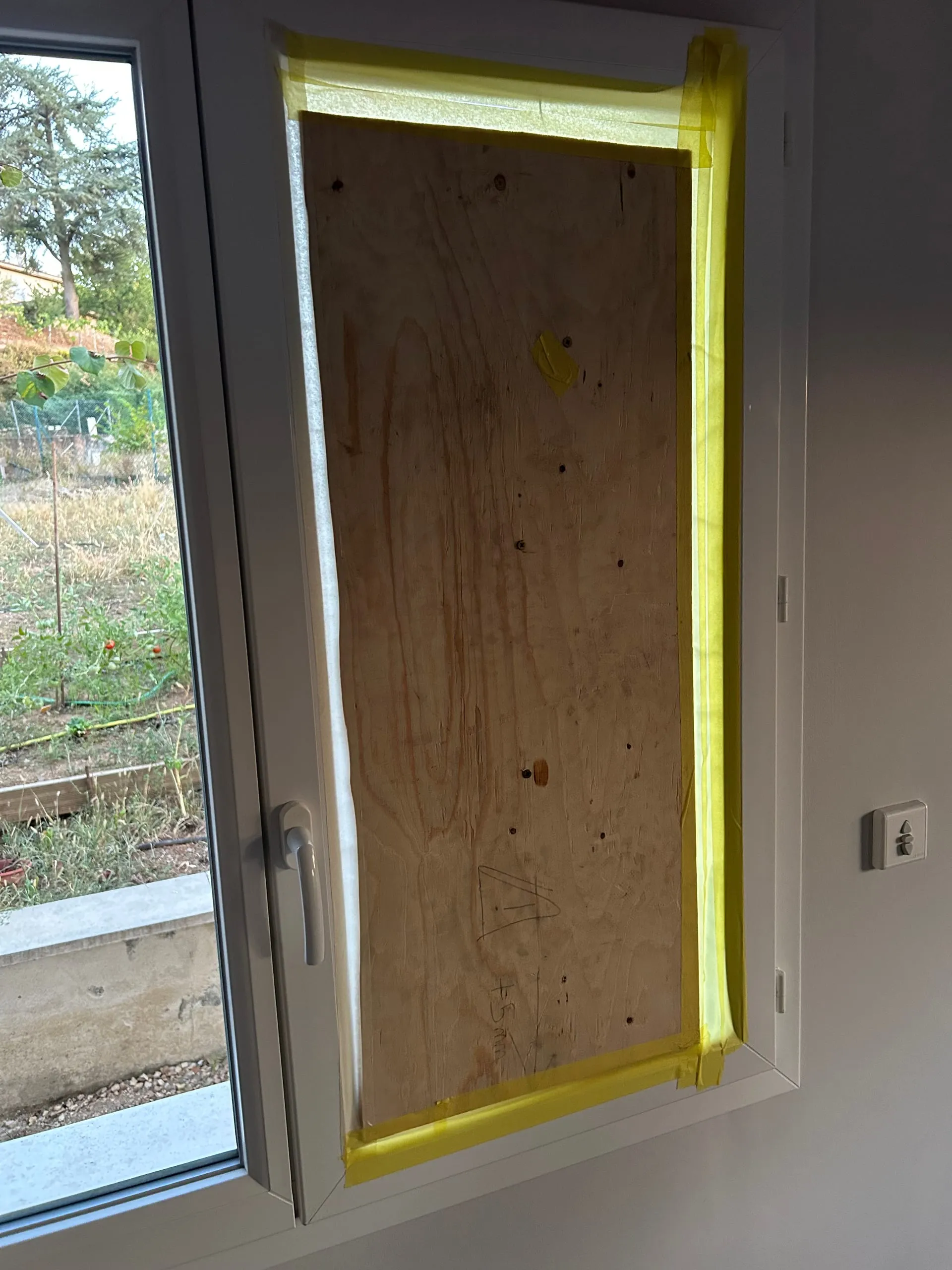 Panneau de contreplaqué fixé dans un ouvrant PVC blanc après le bris du double vitrage.