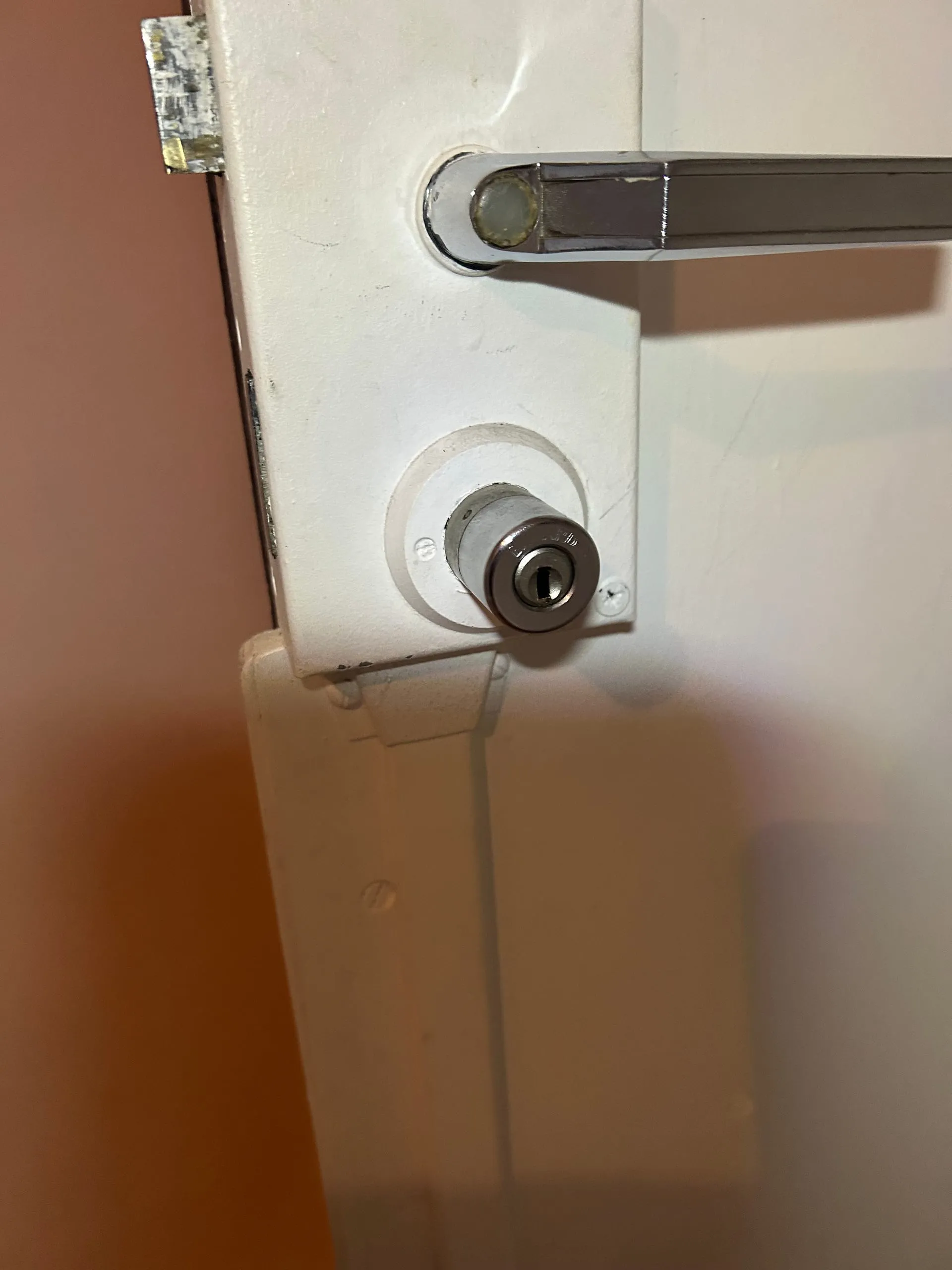 Gros plan sur la poignée et le cylindre de l’ancienne serrure Fichet 2D blanche.