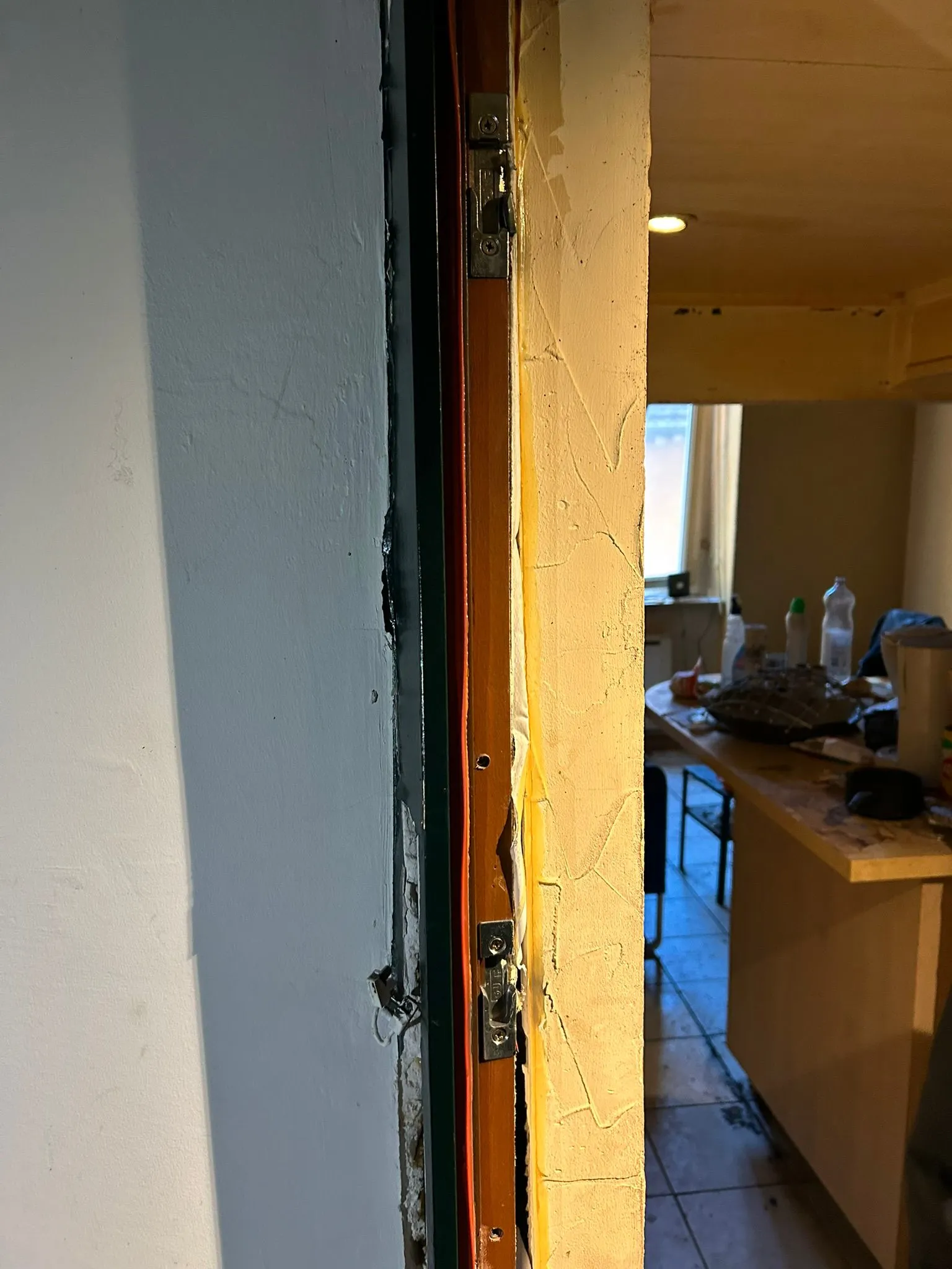 Cadre de porte en bois éclaté à proximité de deux gâches métalliques.