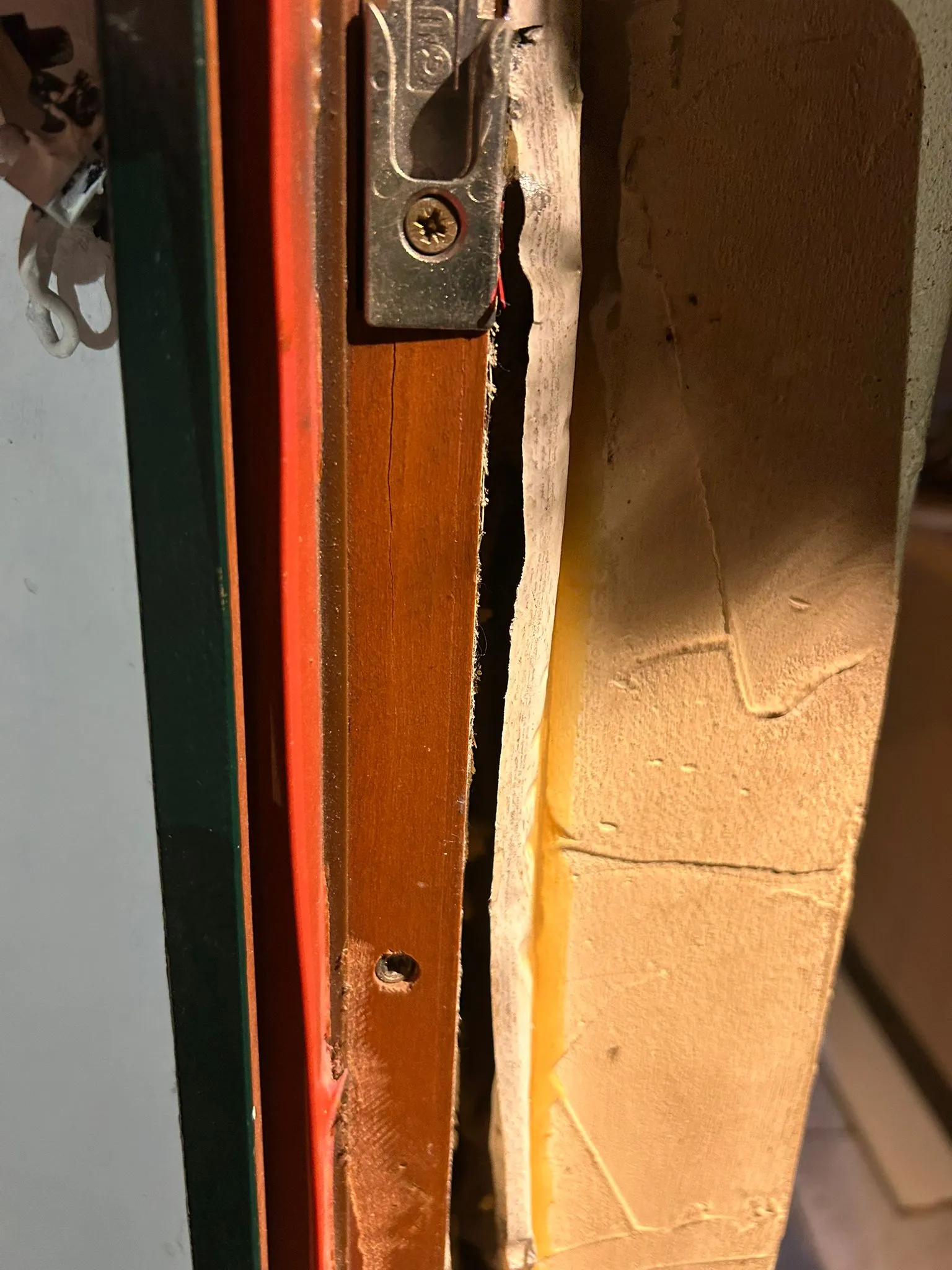 Gâche métallique fixée dans un cadre de porte en bois brun.