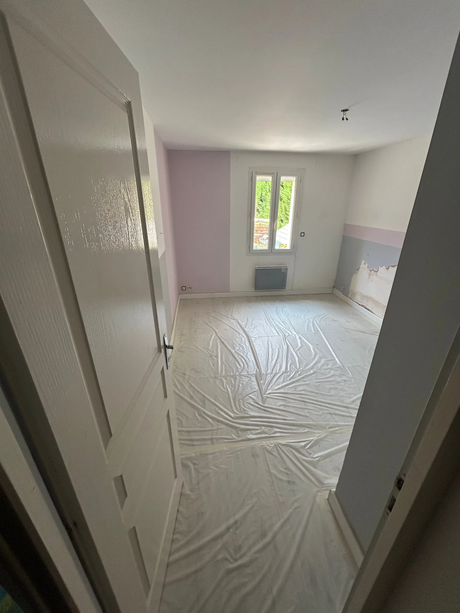 Chambre d’enfant avant rénovation avec murs rose, gris et blanc et zone dégradée en partie basse.