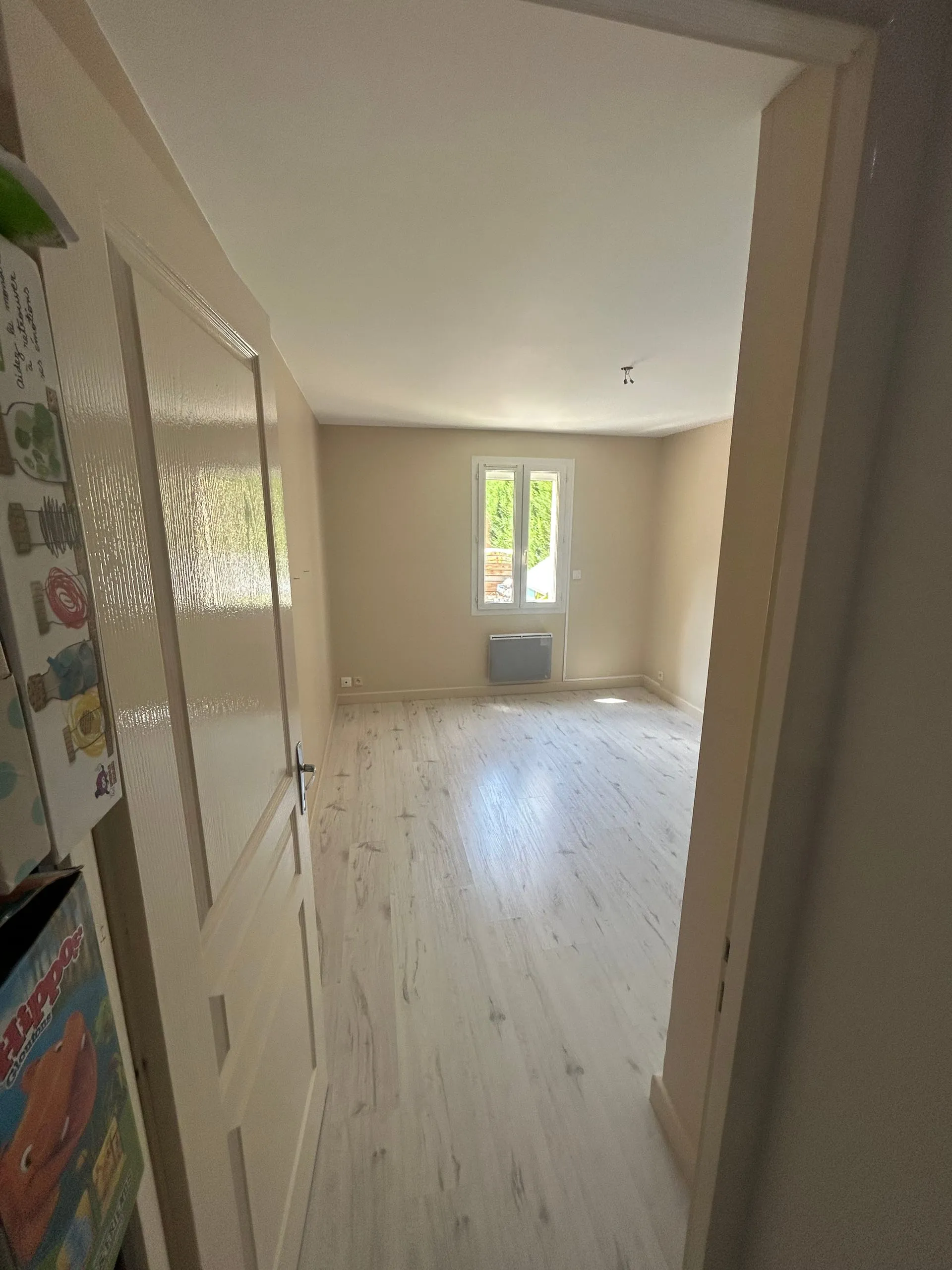 Chambre d’enfant rénovée vue depuis la porte avec murs beige clair et plafond blanc.