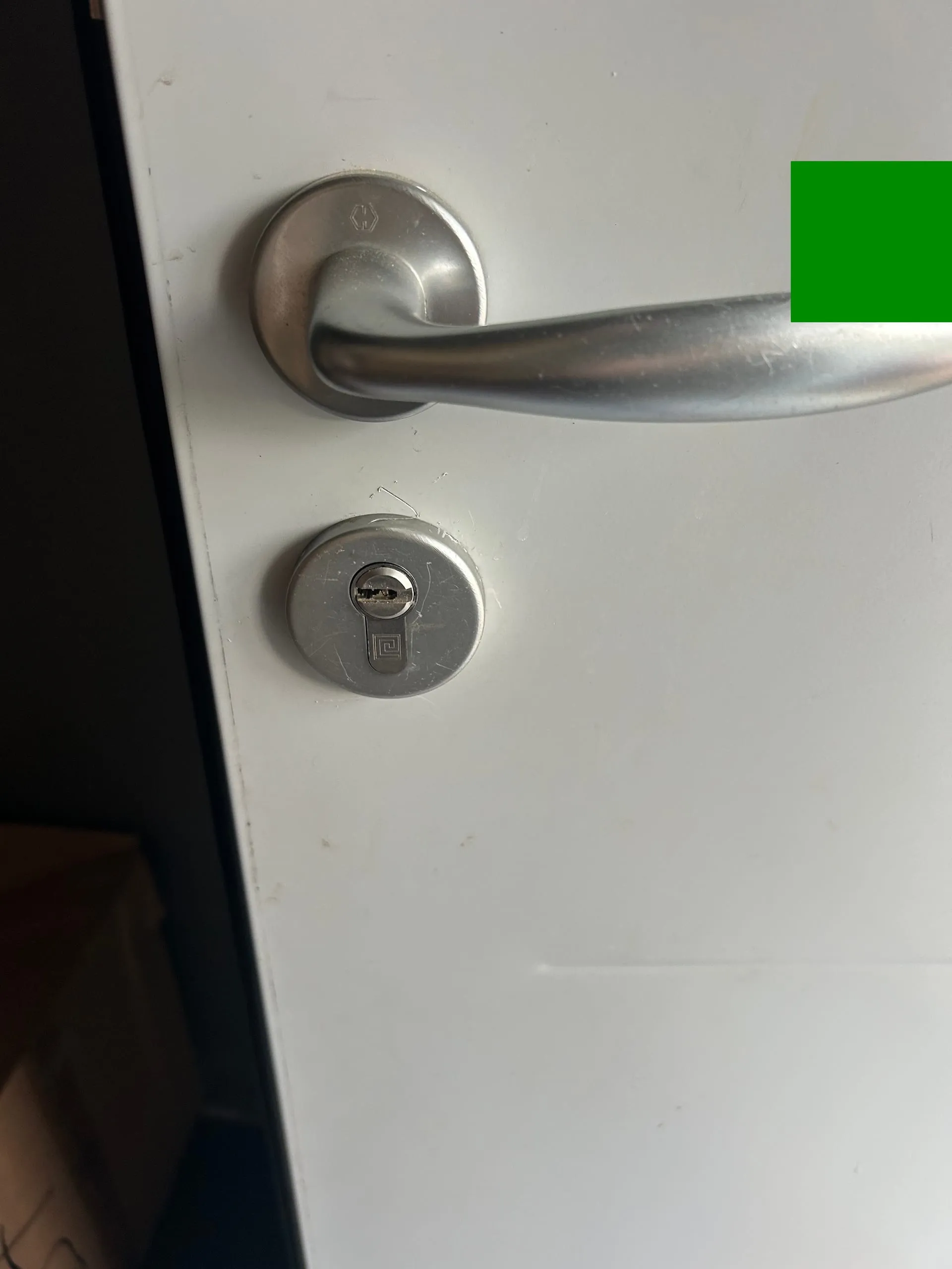 Nouveau cylindre installé sous la poignée métallique d’une porte blanche.