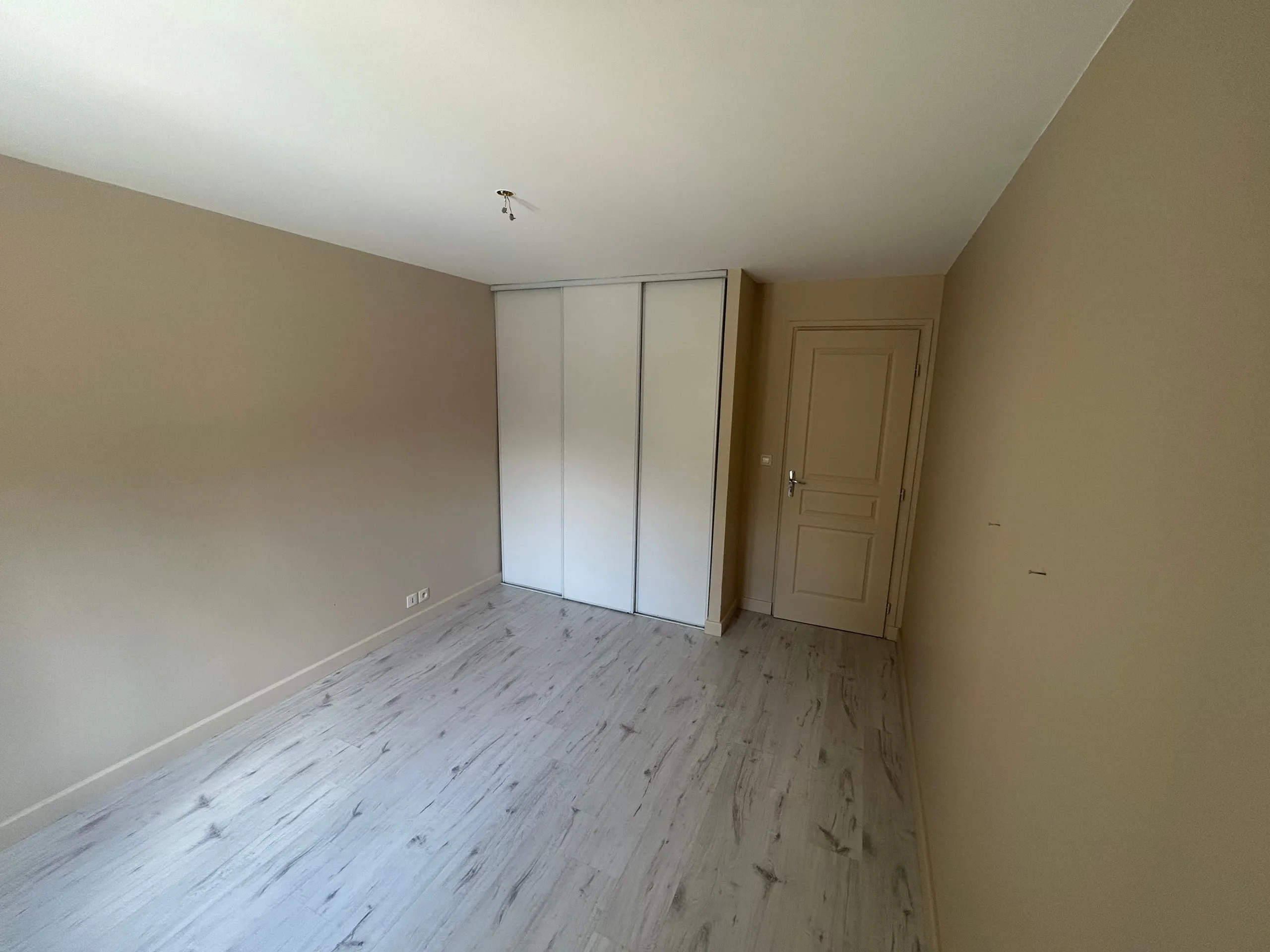 Chambre d’enfant terminée avec murs beige clair, plafond blanc et sol imitation bois clair.