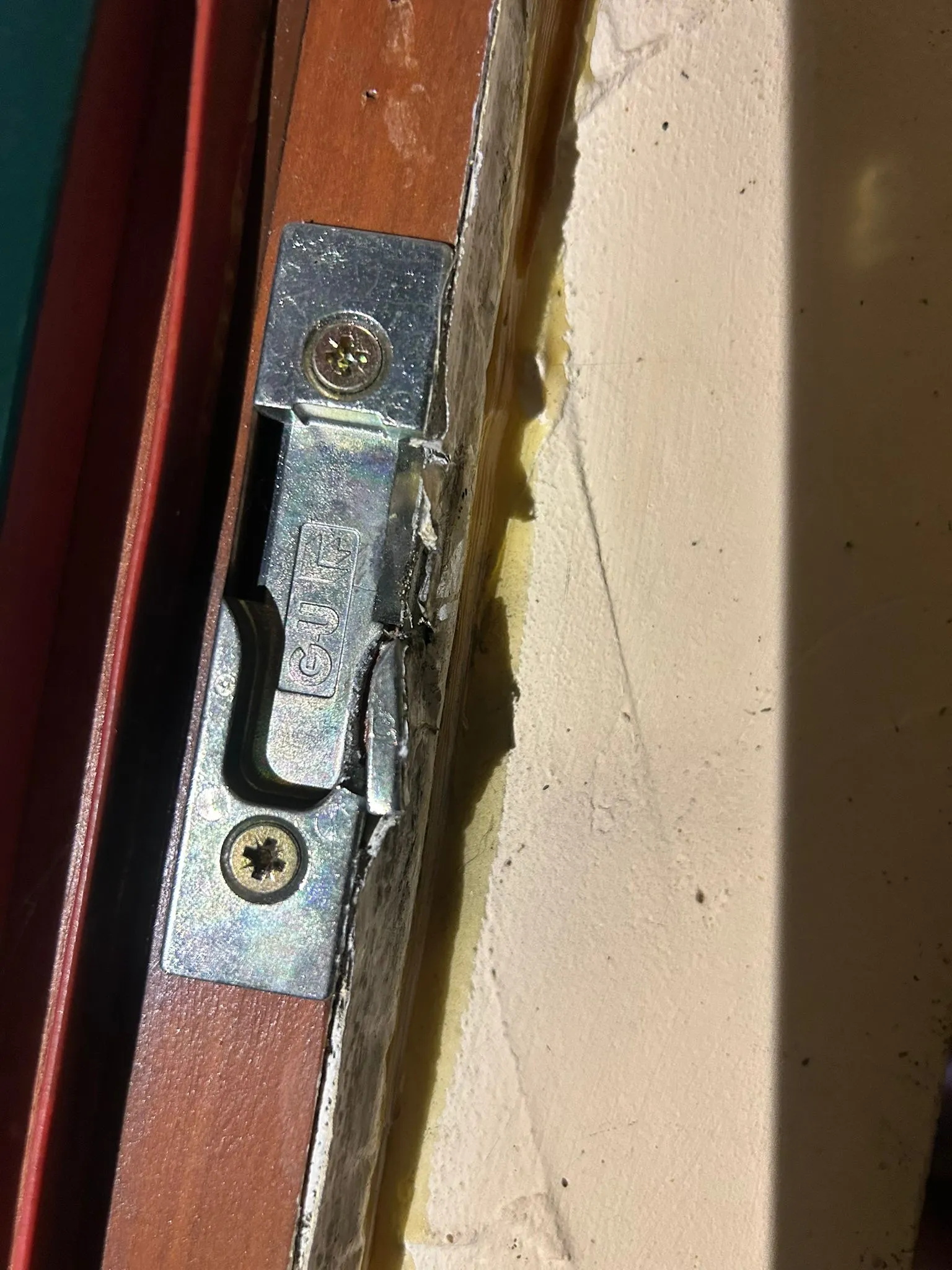 Nouvelle gâche métallique vissée dans le cadre en bois d’une porte.