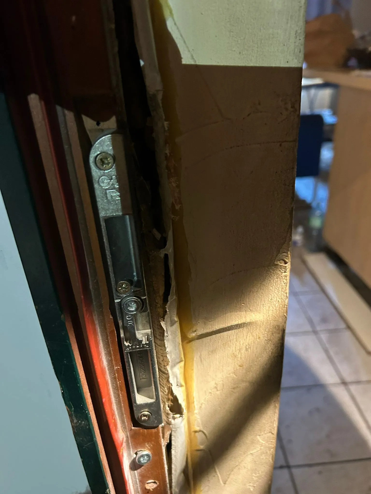 Gros plan sur une gâche métallique et le bois repris autour de la pièce.
