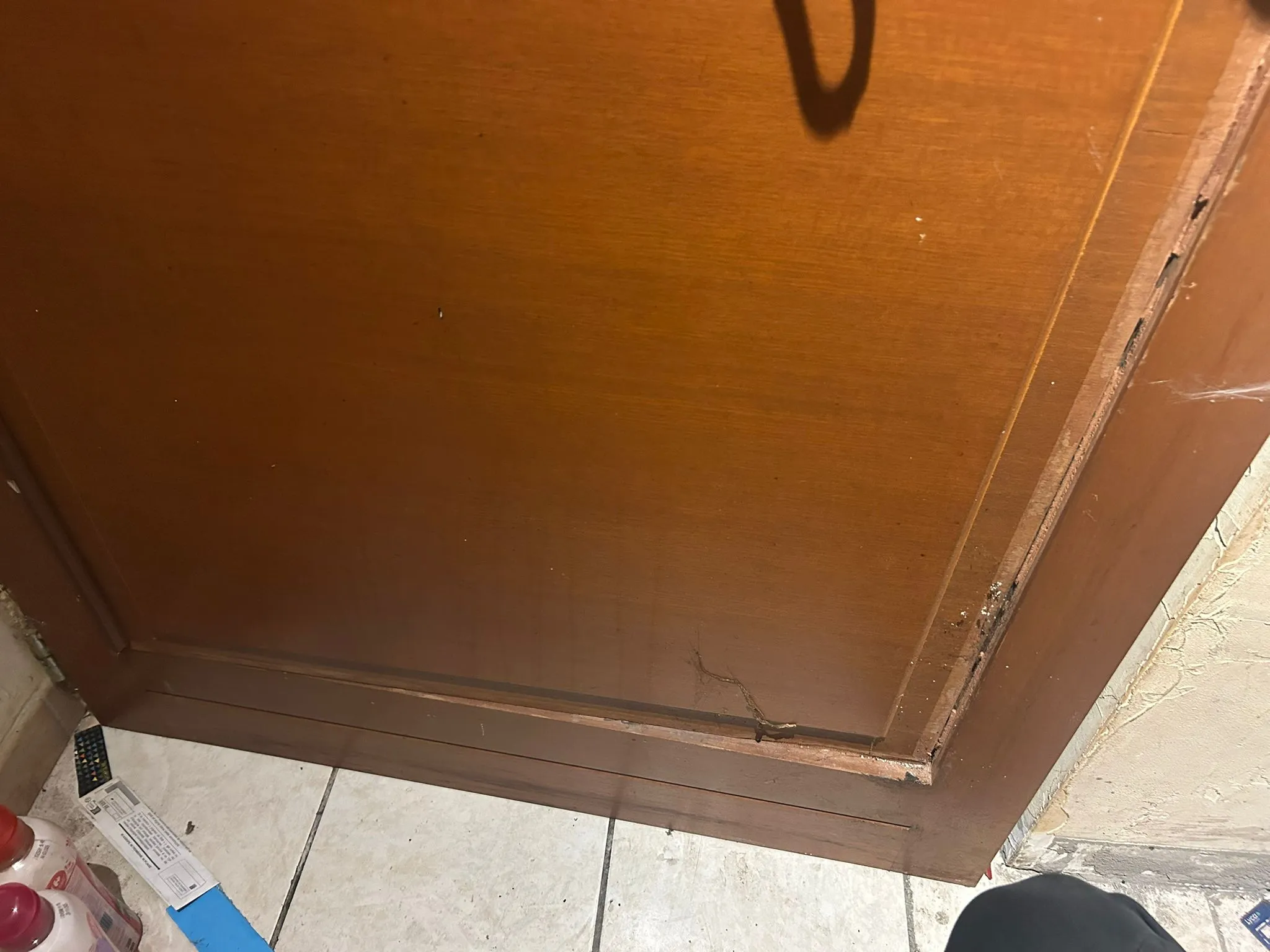 Panneau inférieur d’une porte en bois brun avec une moulure endommagée.