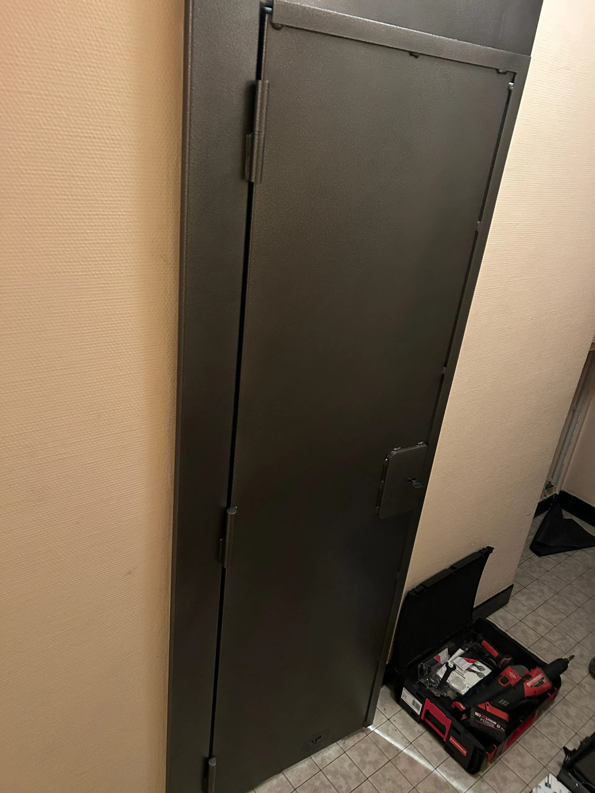 Porte anti-squat en acier anthracite avec ses charnières et sa trappe de serrure, vue depuis le palier.