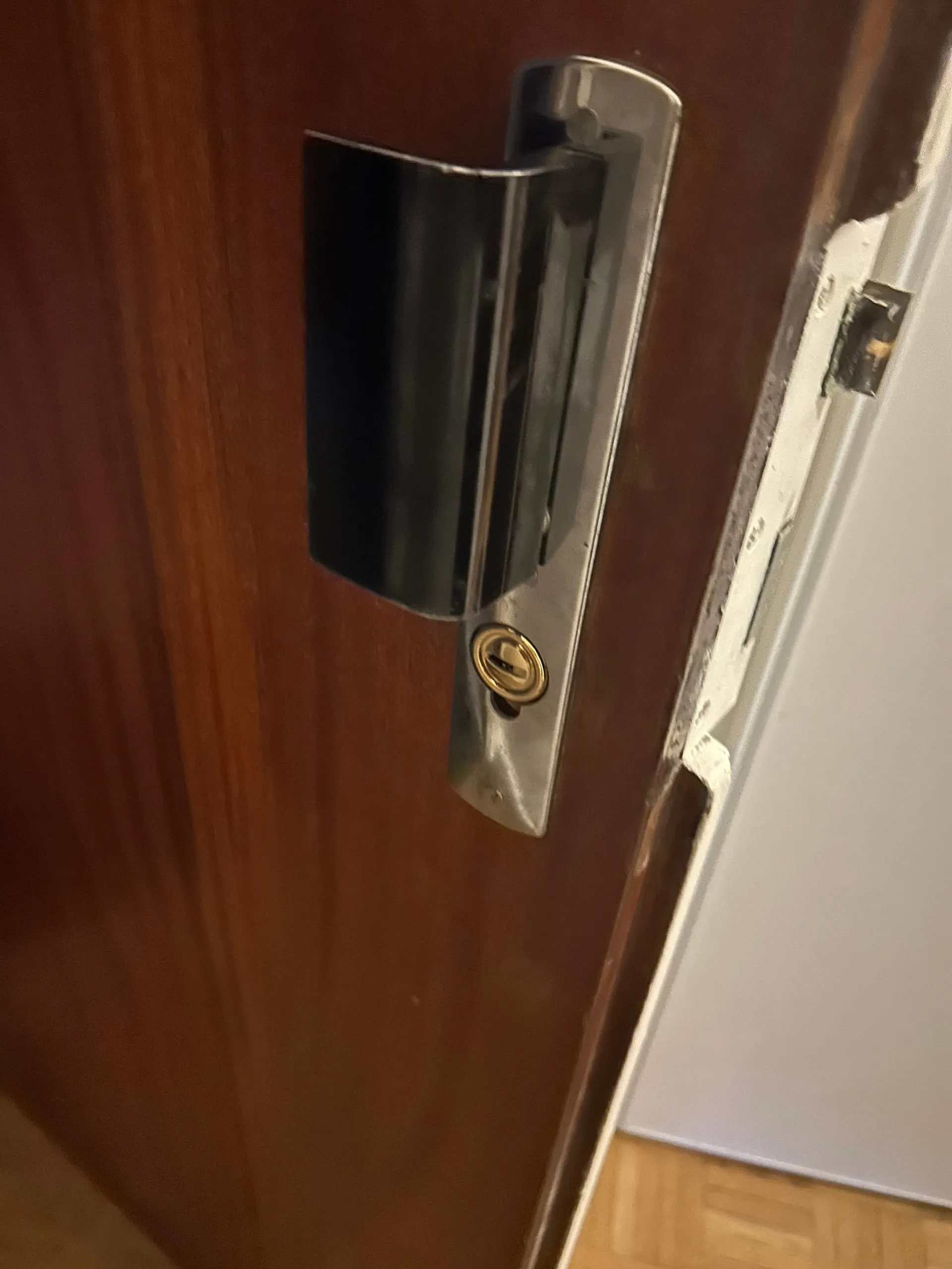 Nouvelle serrure Fichet avec poignée noire et cylindre doré sur une porte en bois.